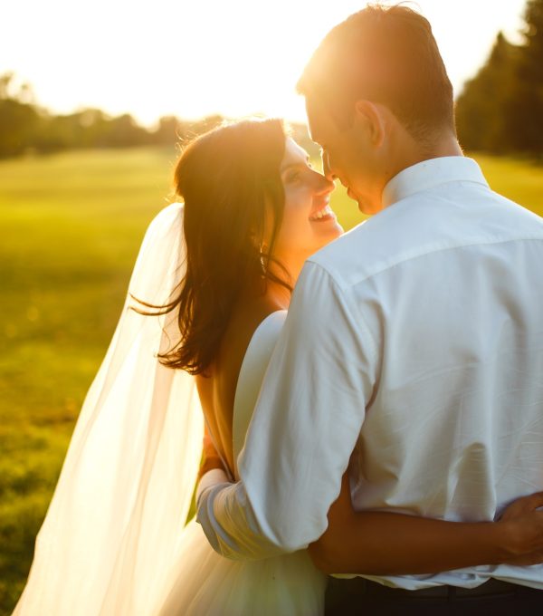 Lovely wedding couple at sunset. Bride, groom in wedding attire with bouquet of flowers. Romantic.